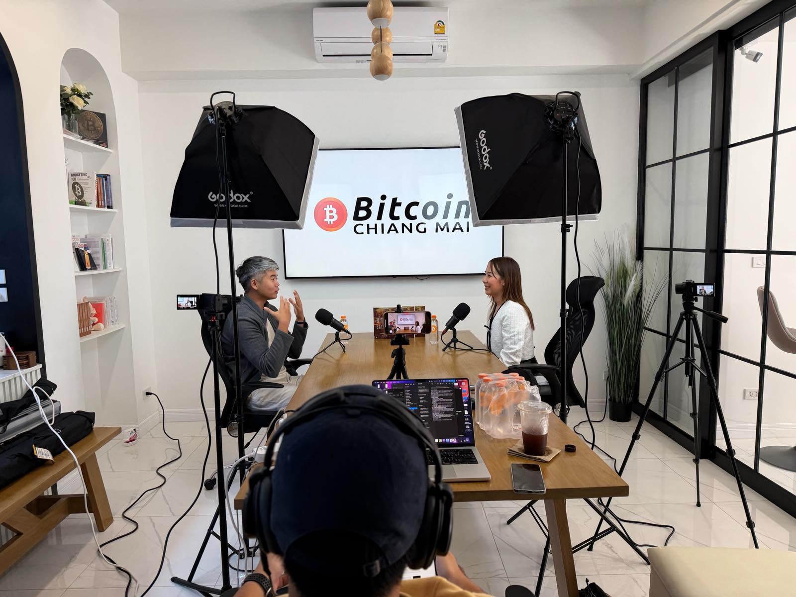 A two-person interview in progress, cameras and softboxes set up around the table