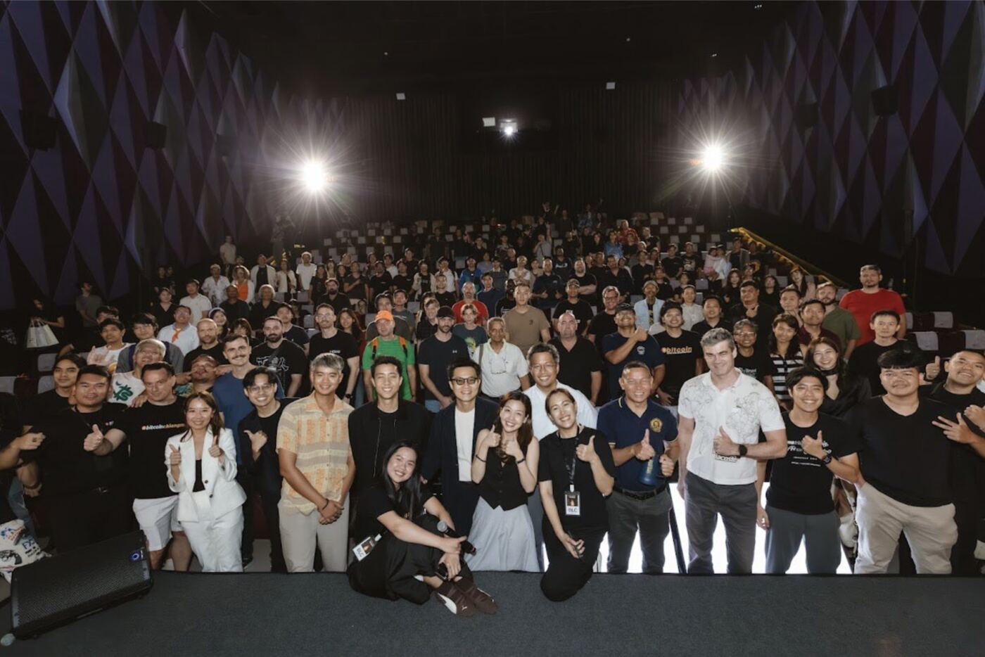 A large group of attendees gathered on stage and in the seats of a cinema after a community event